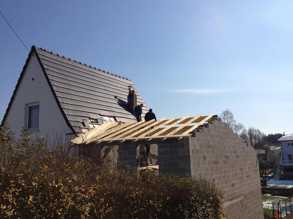 Extension en parpaings avec sa charpente, à côté d'une maison